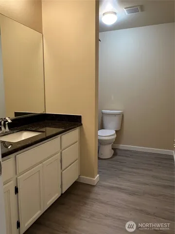 a bathroom with a granite countertop sink and a toilet