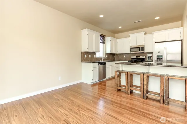 a kitchen with stainless steel appliances granite countertop a stove top oven a sink and white cabinets