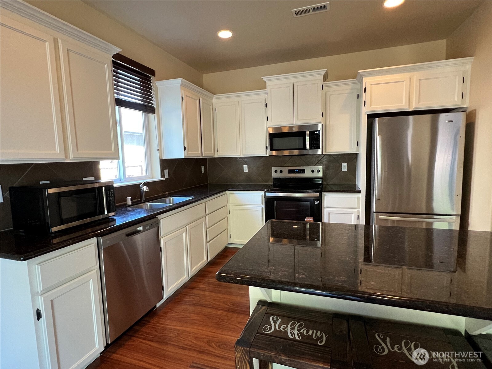 1605 Riddell Avenue Northeast Orting, WA 98360 - Photo 10 of 35 a kitchen with granite countertop a refrigerator a stove a sink a washer and cabinets
