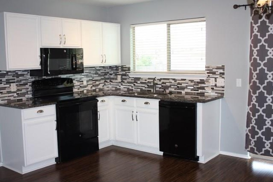 1120 Apollo Circle Round Rock, TX 78664 - Photo 8 of 14 Kitchen featuring white cabinetry, dark speckled countertops, a mosaic tile backsplash, black appliances, and dark wood-finish flooring