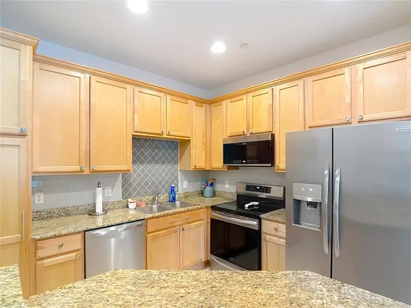 a kitchen with granite countertop a refrigerator and a stove top oven
