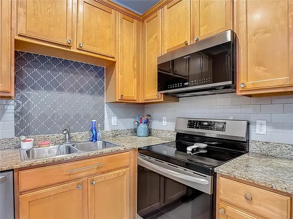 a kitchen with stainless steel appliances granite countertop a sink a stove a microwave oven and cabinets