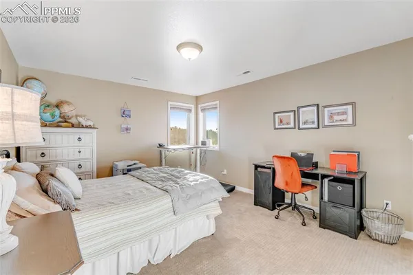a bedroom with a bed a desk and chair next to a window