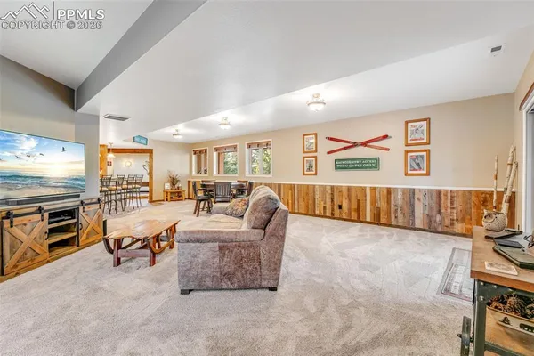 a living room with furniture a flat screen tv and a refrigerator