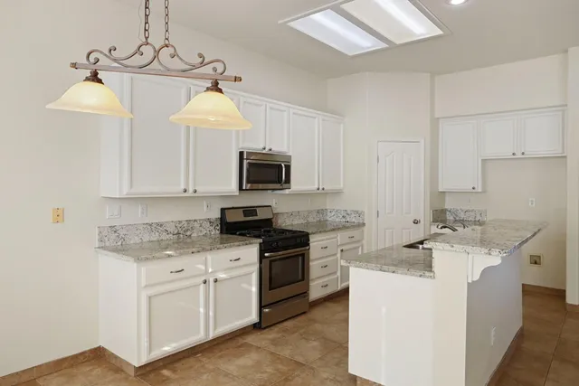 a kitchen with stainless steel appliances granite countertop a sink a stove top oven a counter space and cabinets