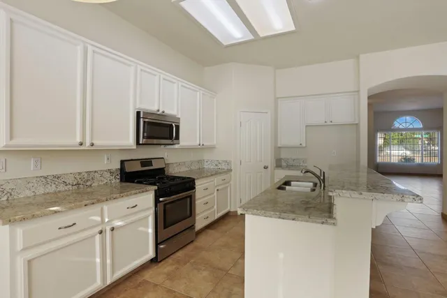 a kitchen with granite countertop white cabinets and stainless steel appliances