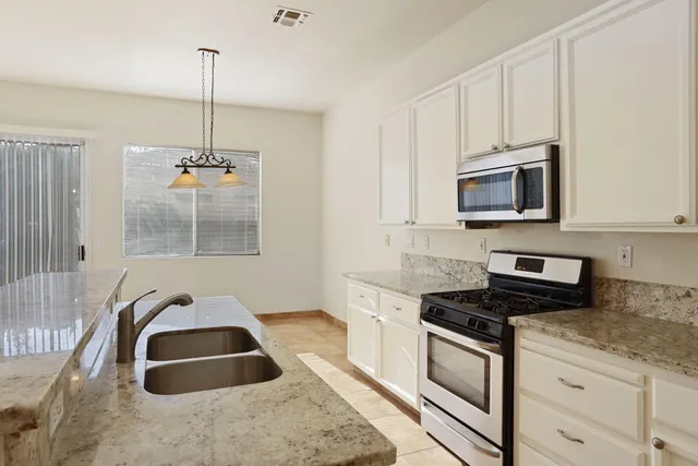 a kitchen with stainless steel appliances granite countertop a stove a sink and a microwave