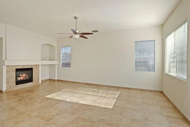 an empty room with windows and fireplace