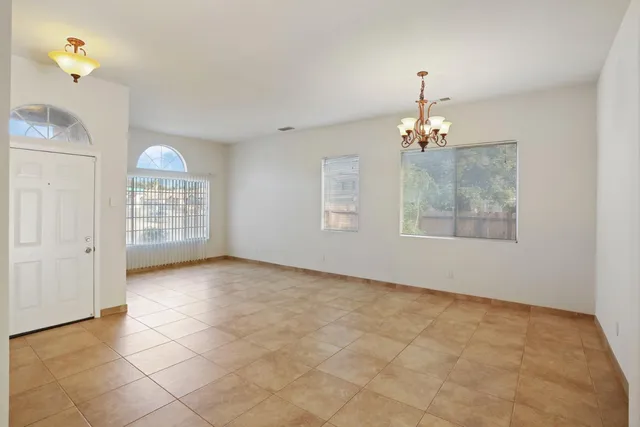 an empty room with chandelier fan and windows