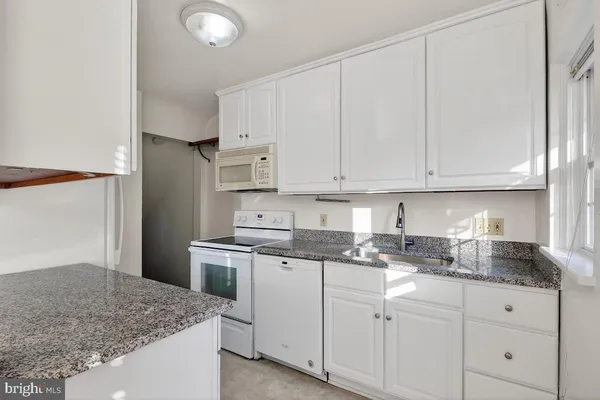a kitchen with granite countertop white cabinets and white appliances