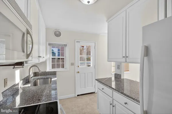 a kitchen with granite countertop a sink a stove and refrigerator