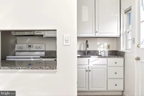 a kitchen with white cabinets and sink
