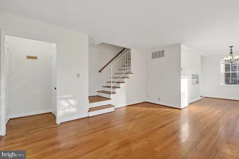 a view of an empty room with wooden floor and stairs