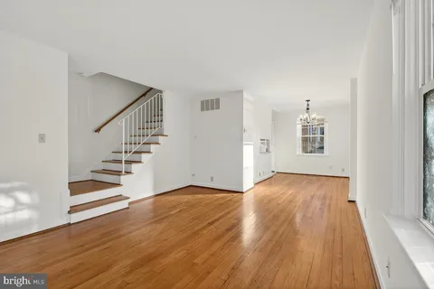 a view of an empty room with wooden floor and stairs
