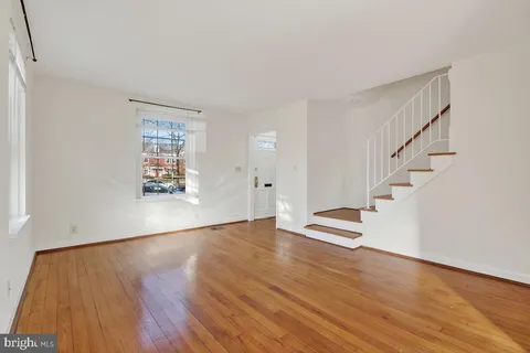 a view of an empty room with wooden floor and stairs