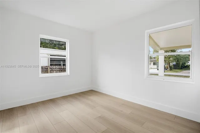 a view of an empty room with wooden floor and a window