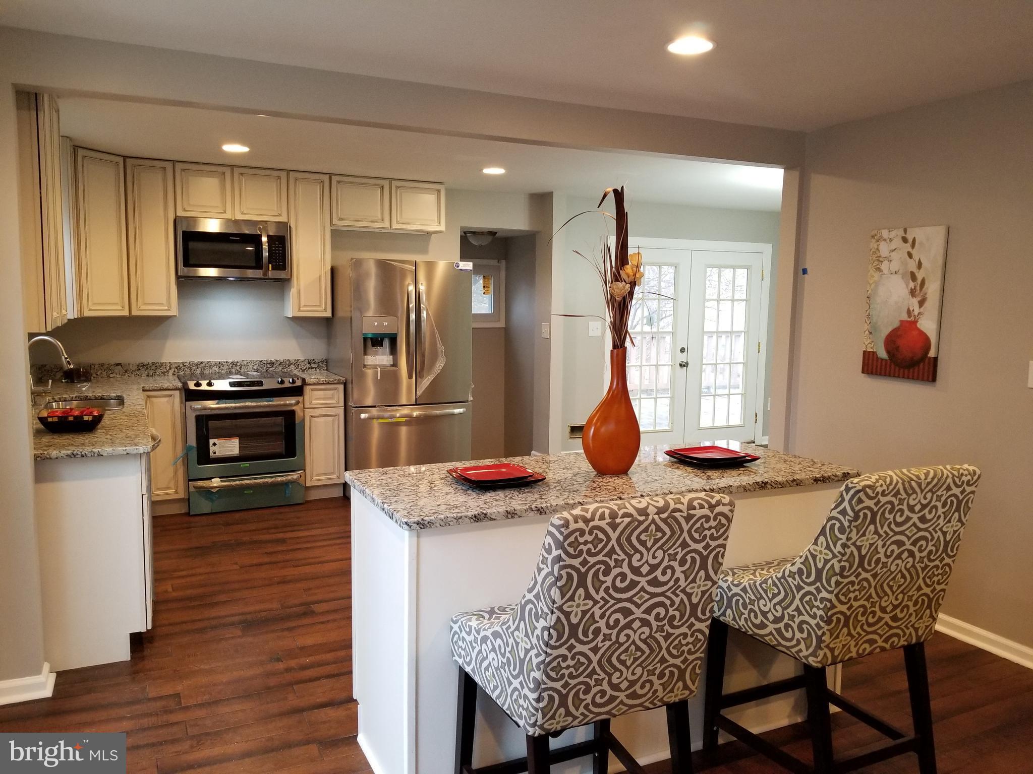 3704 Cassen Road Randallstown, MD 21133 - Photo 1 of 15 a kitchen with stainless steel appliances granite countertop a kitchen island hardwood floor and a sink