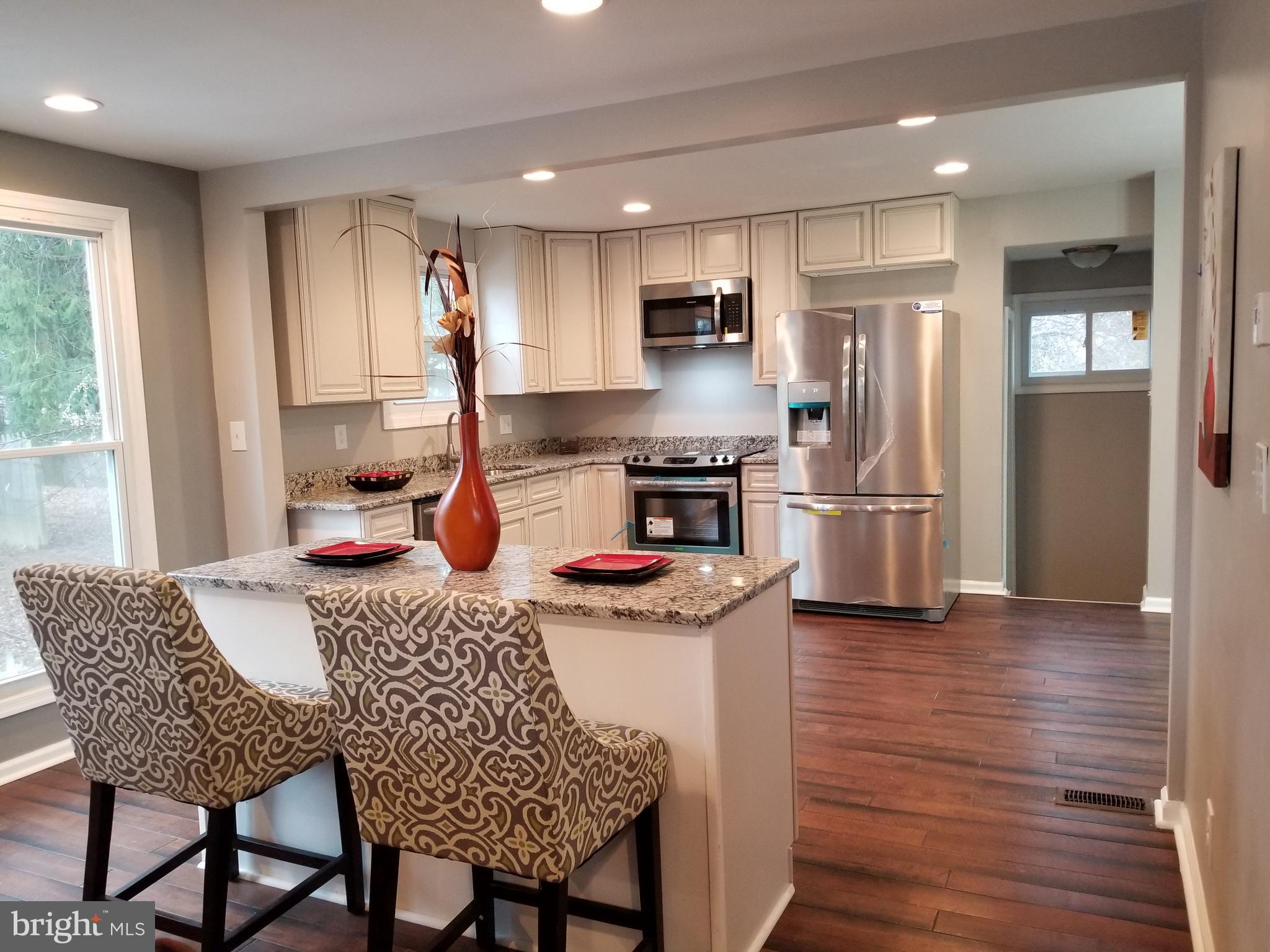 3704 Cassen Road Randallstown, MD 21133 - Photo 4 of 15 a kitchen with stainless steel appliances granite countertop a stove refrigerator a sink dishwasher a dining table and chairs with wooden floor