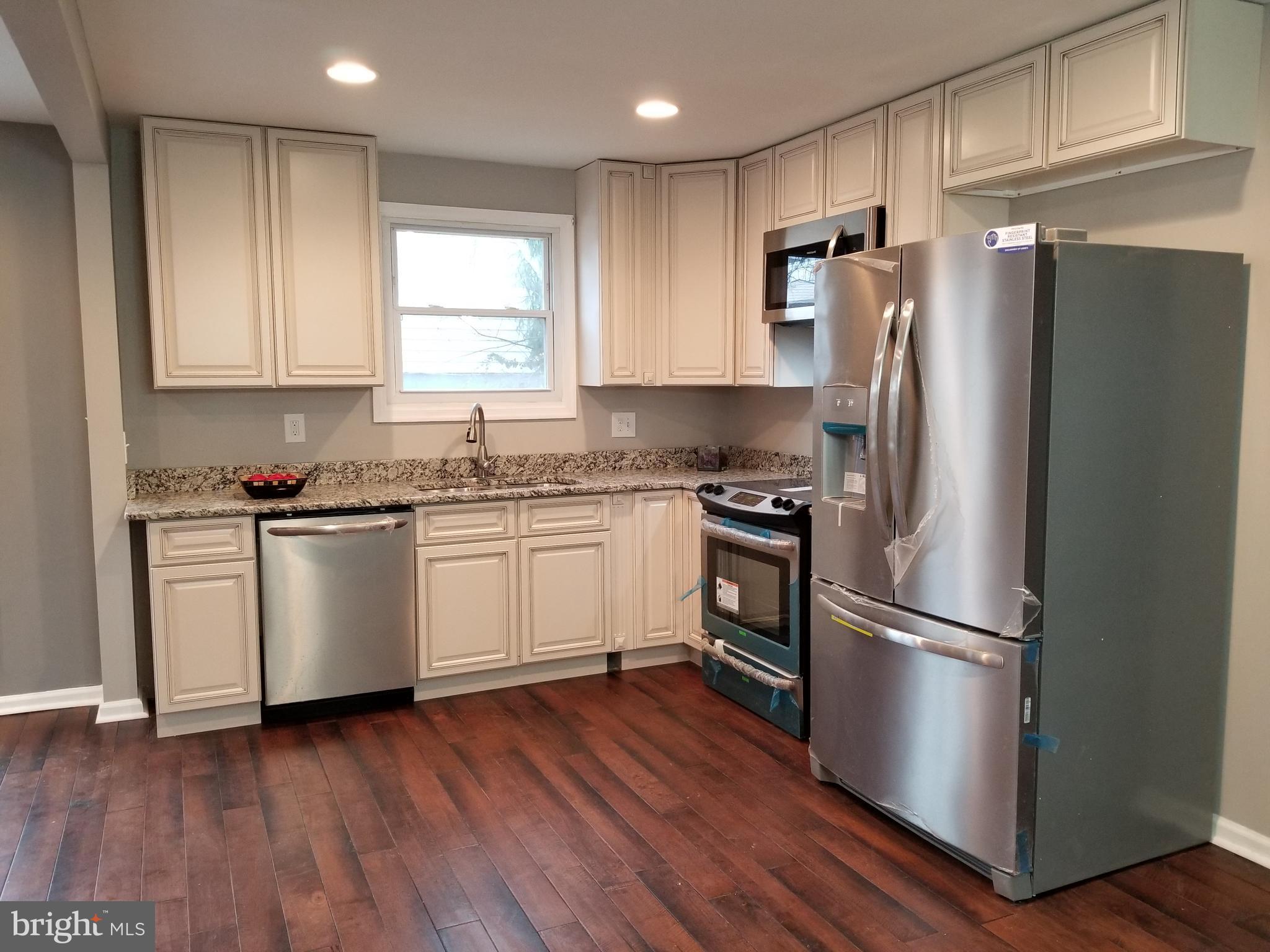 3704 Cassen Road Randallstown, MD 21133 - Photo 5 of 15 a kitchen with a refrigerator wooden floor a window cabinets and stainless steel appliances