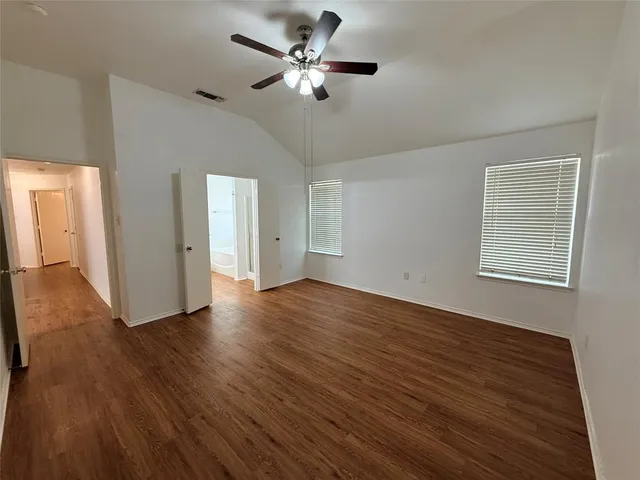 a view of an empty room with a window and wooden floor