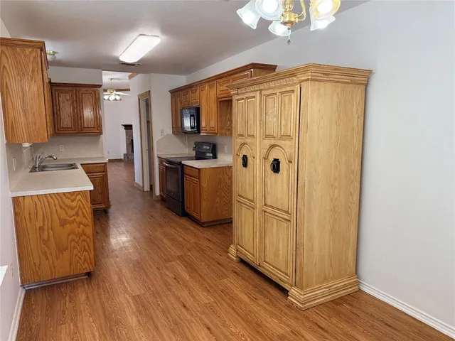 a kitchen with stainless steel appliances granite countertop a refrigerator a stove a sink and dishwasher with wooden floor