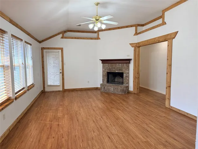 a view of empty room with wooden floor and fireplace