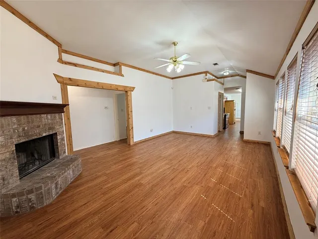 a view of empty room with wooden floor and fireplace