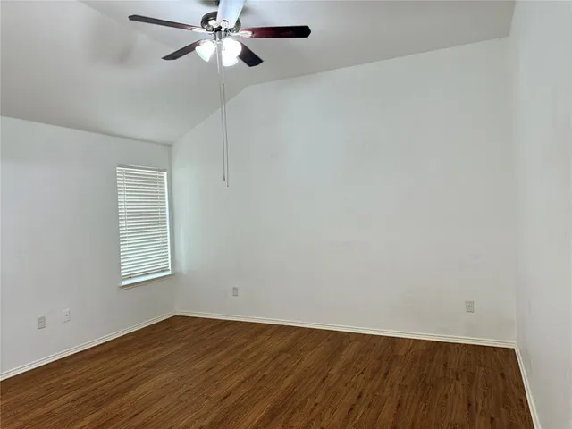 an empty room with wooden floor closet and windows