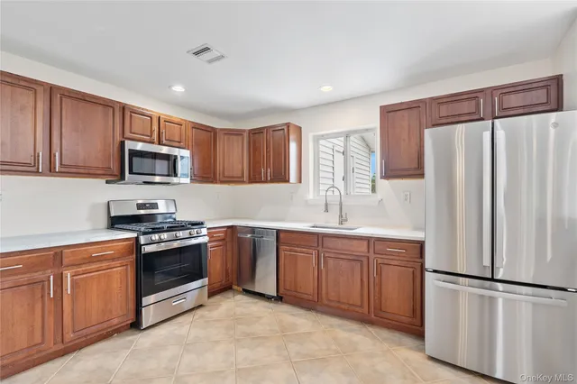 a kitchen with stainless steel appliances granite countertop a refrigerator stove a sink and dishwasher with wooden cabinets