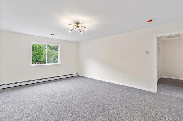 an empty room with windows and chandelier fan
