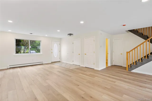 a view of an empty room with wooden floor and windows