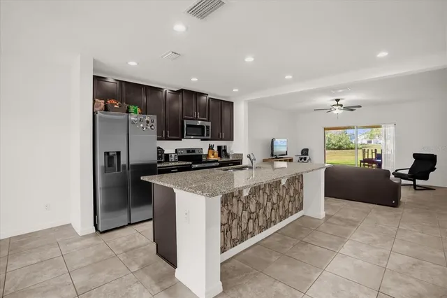 a large kitchen with stainless steel appliances granite countertop a refrigerator and a stove top oven