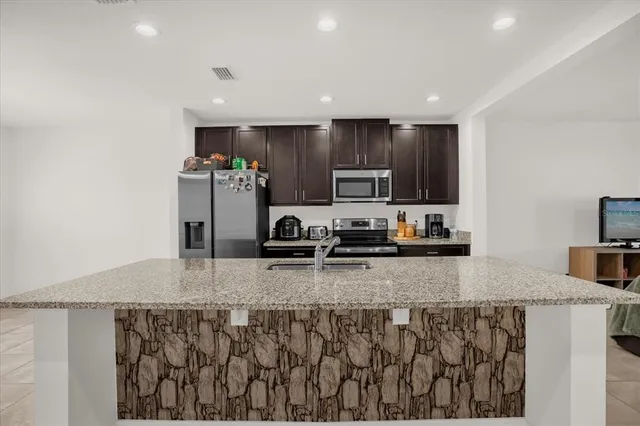 a kitchen with stainless steel appliances granite countertop a sink a stove top oven a refrigerator and dishwasher