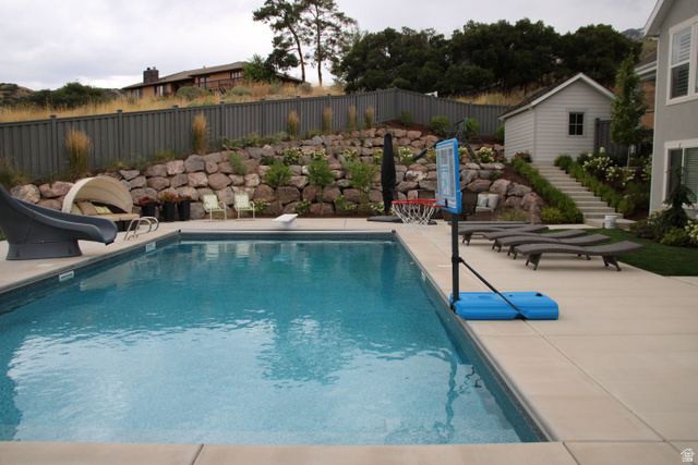 7 Elk Court Alpine, UT 84004 - Photo 9 of 10 In-ground swimming pool with a concrete surround, stone retaining wall, and terraced landscaping