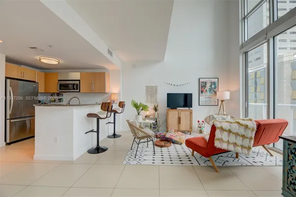 a living room with furniture a flat screen tv and a refrigerator
