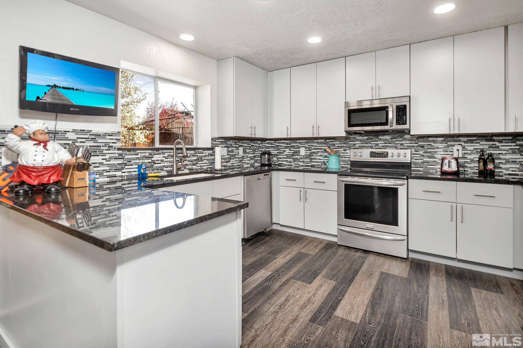 3435 Bowie Road Reno, NV 89503 - Photo 8 of 22 a kitchen with stainless steel appliances granite countertop a stove and white cabinets