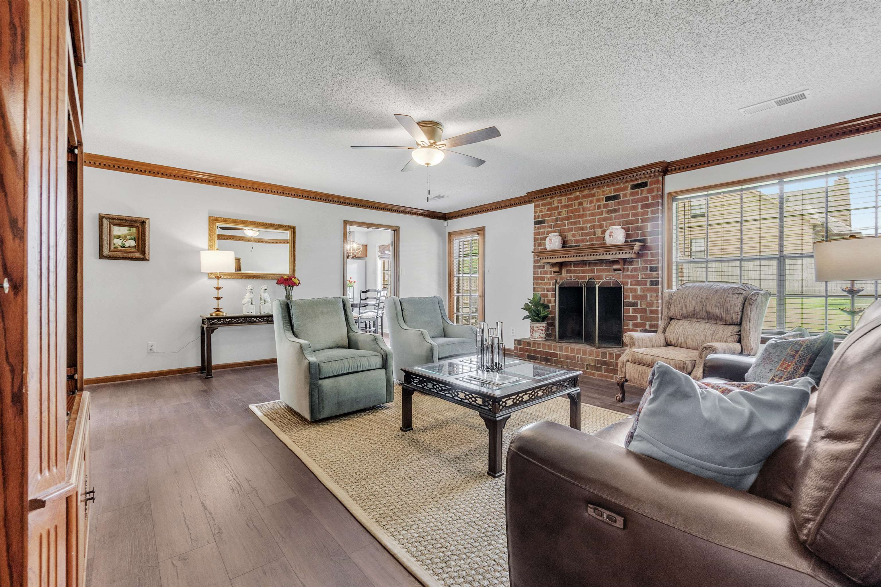 7255 Barnstable Road Memphis, TN 38125 - Photo 6 of 27 Living room with ceiling fan, baseboards, wood finished floors, ornamental molding, and a fireplace