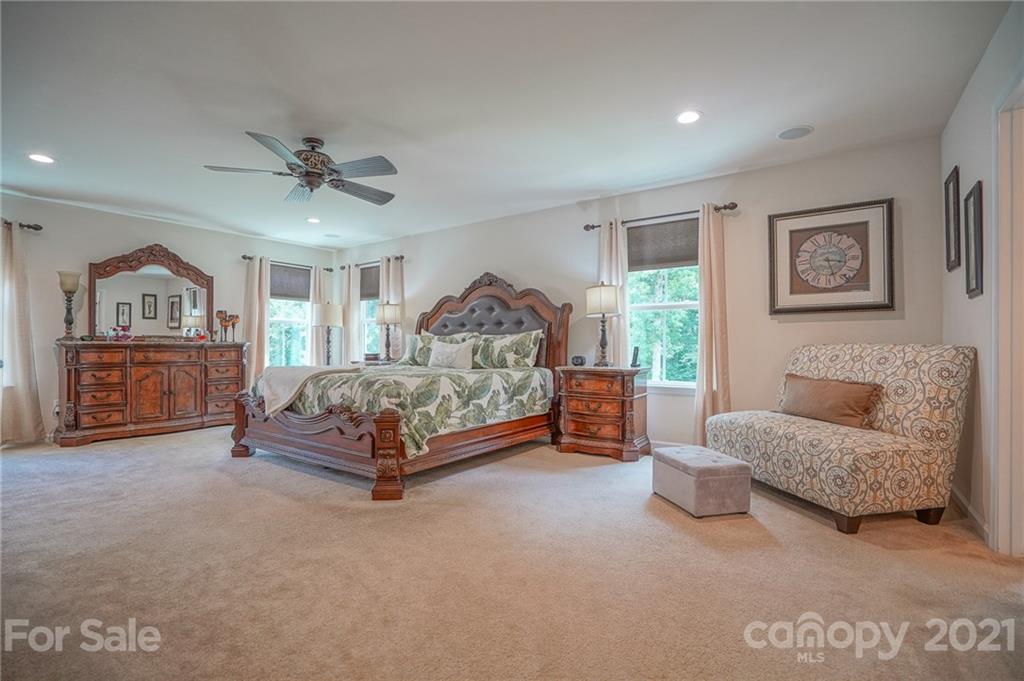 7788 East Berkeley Road, Unit 1106 Denver, NC 28037 - Photo 34 of 48 a spacious bedroom with a bed a couch and a painting on the wall