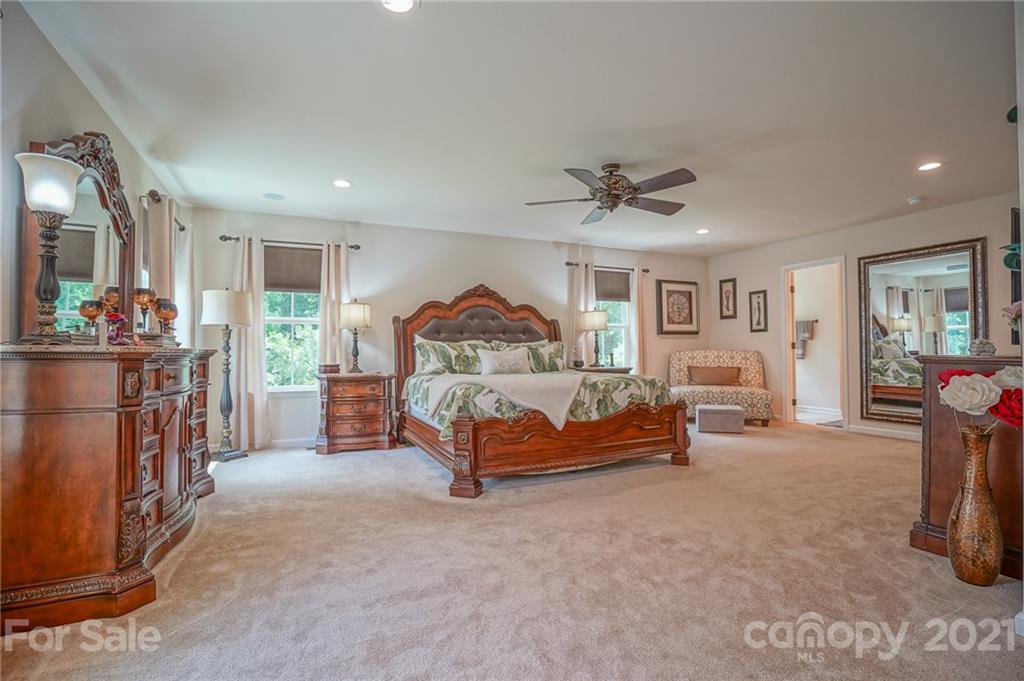 7788 East Berkeley Road, Unit 1106 Denver, NC 28037 - Photo 35 of 48 a spacious bedroom with a bed and a chandelier
