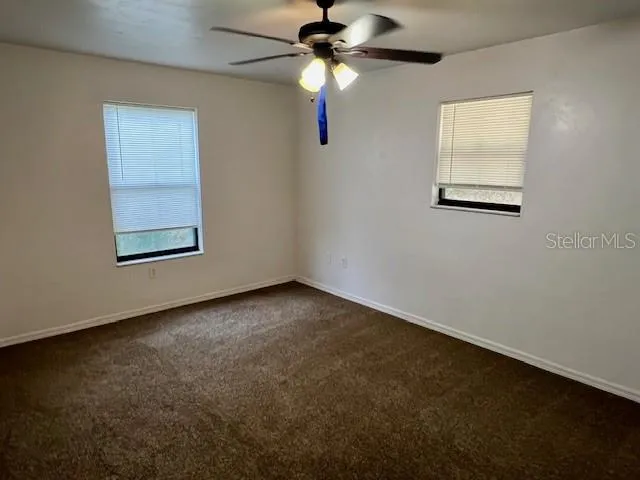 an empty room with windows and fan