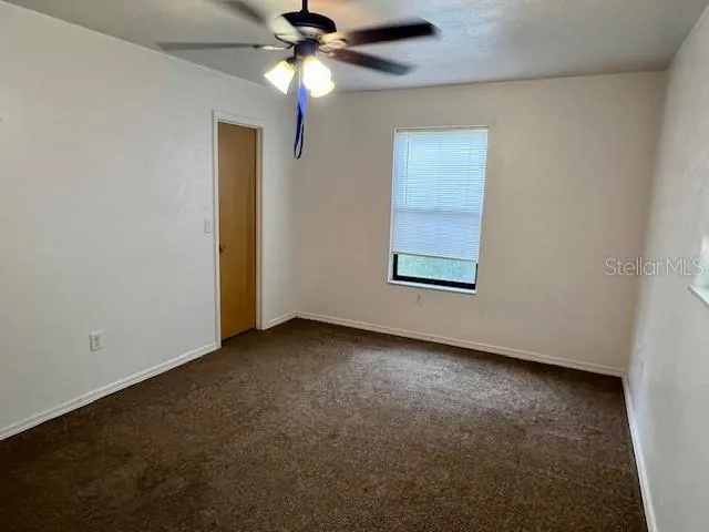 an empty room with a window and a fan