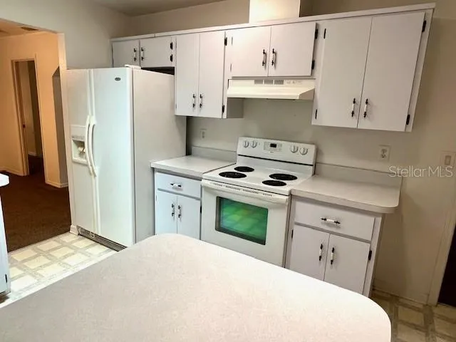 a kitchen with stainless steel appliances a refrigerator stove and white cabinets