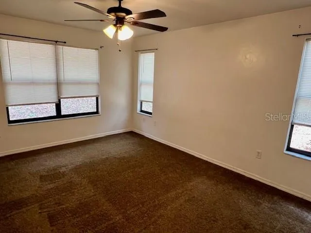 an empty room with windows and fan