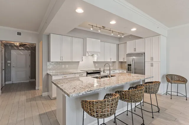 a kitchen with kitchen island granite countertop wooden floors and refrigerator