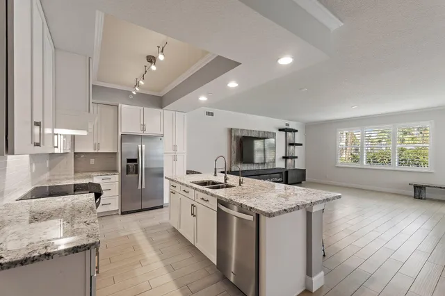 a kitchen with granite countertop a sink stainless steel appliances and white cabinets