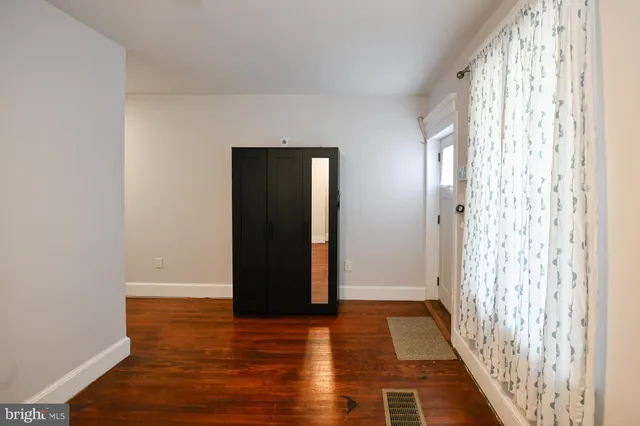 a view of a hallway with wooden floor and a bathroom
