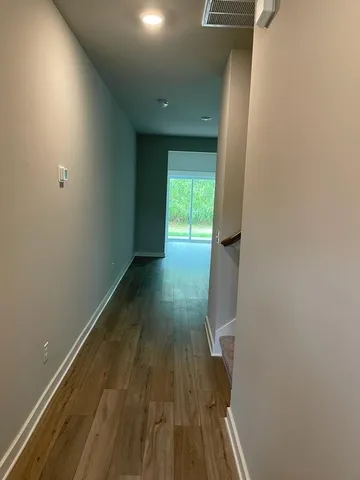 a view of a hallway with wooden floor and a bathroom