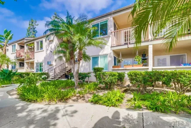 a front view of a multi story residential apartment building with yard and bench