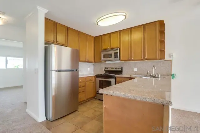 a kitchen with a refrigerator a stove a sink a washer dryer and cabinets