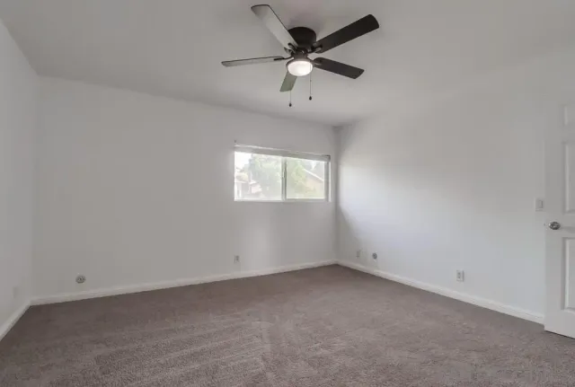 an empty room with a window and a fan